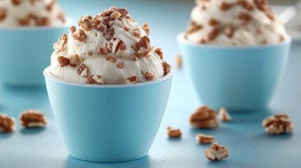 Close-up of creamy white ice cream topped with chopped nuts served in small blue cups with a soft focus background