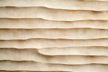 Close-up of beige sand dunes with soft undulating ridges and smooth texture creating a natural wavy pattern under soft lighting