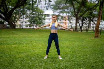 A woman is standing in a park, wearing a yellow towel and doing a push up