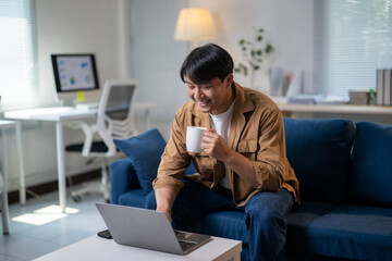 A man is sitting on a couch with a laptop in front of him