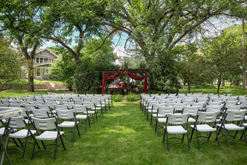 Outdoor wedding ceremony setup with white chairs and decorated pergola