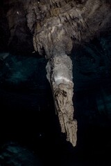 Stalactite hangs dramatically from a dark cave ceiling.