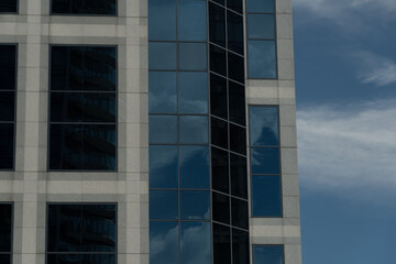 Blue sky over Vancouver cityscape  reflected in tall windows of a modern glass skyscraper, showcasing the architectural details and warm summer colors
