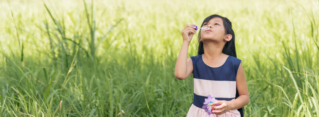 Banner happy girl playful foam bubbles in green playground summer outdoors. Funny Cheerful girl in the park happiness times. Banner Bubbles blowing soap playful outdoor nature park with copy space