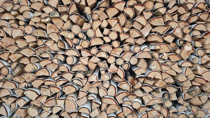 Stack of chopped firewood arranged in pile, rustic background. Natural wooden logs for fireplace, heating, camping or decoration. Close-up texture of birch and pine wood.