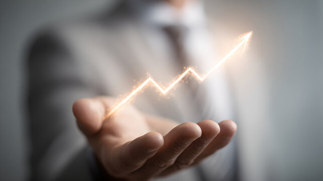 Businessman's hand holding a glowing orange line graph showing upward trend and business growth.
