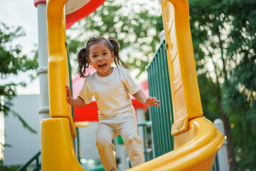 happy toddler baby girl sliding and playing at playground