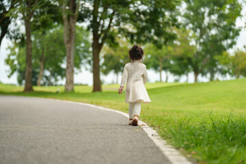 toddler girl walk along a pathway in park