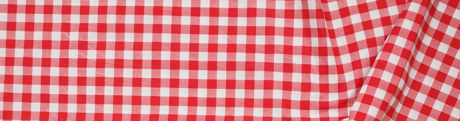 Closeup of a red and white checkered napkin or tablecloth texture. picnic cloth crumpled. Food decor element. Kitchen accessories. Top view background.