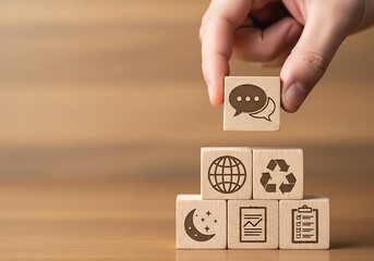 Hand stacking wooden blocks with icons representing communication, global, recycle, and planning