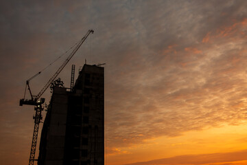 Silhouette of construction building and cranes at twilight sky.