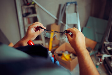 Construction Worker Putting on Protective Glasses for Work. Specialist using  personal protective...