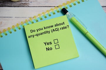 Do you know about any-quantity AQ rate write on sticky notes isolated on Wooden Table. A person is...