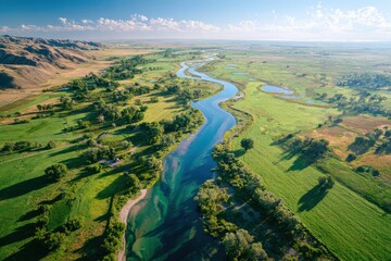 Scenic Aerial View of Serene River Meandering Through Lush Green Landscape with Rolling Hills and Clear Blue Sky Illuminated by Warm Sunlight