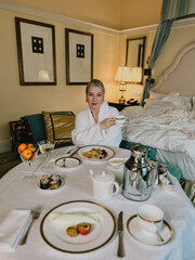 A woman enjoying a leisurely breakfast in a lavish hotel room