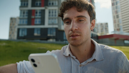 Caucasian man looking at screen mobile phone smartphone cellphone technology internet online chatting messages social networks smile male guy businessman business city communication outdoors gadget