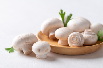 White Button mushroom or Champignon mushroom (Agaricus bisporus) on wooden plate, Food ingredient