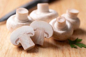 White Button mushroom or Champignon mushroom (Agaricus bisporus) on cutting wooden board, Food...