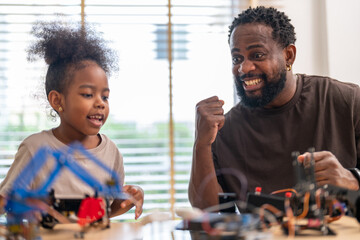 African father and daughter playing with stem robot kit, stem toys for kids fun learning and creativity at home, coding and building robots educational play activities, engineering skills development