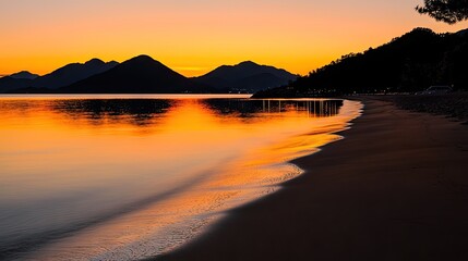 Golden sunset over tranquil beach and mountains.