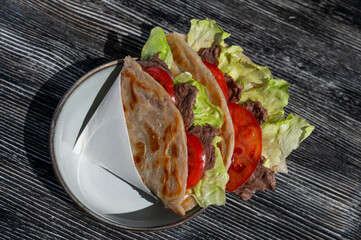 Homemade flatbread with beef and tomatoes on a table in a cafe. 