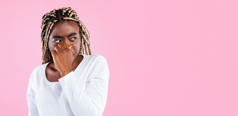 Displeased african american woman plugging her nose, smells something stinky and unpleasant,...