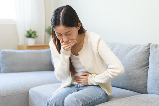 Unhappy pregnant asian young woman, pain girl suffering from nausea, having vomit feeling sick covering mouth, touching belly having problem throwing up from food poisoning, lady with morning sickness