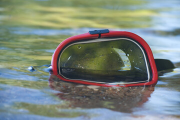 Snorkeling mask resting on the surface of a clear, shallow body of water.