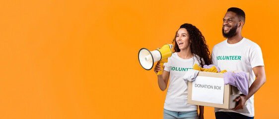 Charity And Volunteering. Couple Of Multiethnic Volunteers Holding Donation Box And Talking In...