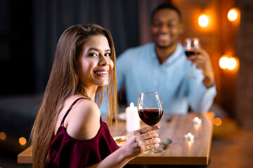Valentine's Day Celebration. Happy Interracial Couple In Love Having Romantic Dinner In Restaurant, Drinking Wine, Smiling At Camera, Multiracial Lovers Dining In Elegant Atmosphere, Selective Focus