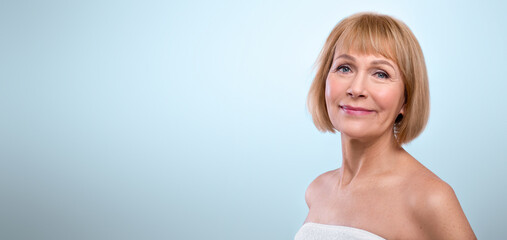 Natural beauty. Portrait of feminine senior woman in towel having smooth silky skin, posing on...