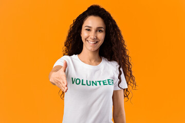 Cheerful Volunteer Woman Offering Hand For Handshake Greeting To Camera Posing Standing Over Yellow...