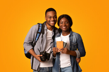 Tourists Couple Concept. Happy african american lovers holding passports with tickets and photo...