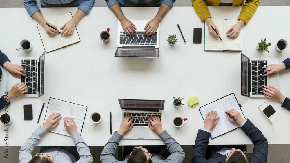 Poster top view of a business meeting with a team collaborating around a table with laptops and notebooks