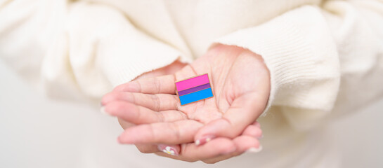 Bisexuality Celebrate Day and LGBT pride month, LGBTQ or LGBTQIA concept. Hand holding purple, pink and blue flag shape for Lesbian, Gay, Bisexual, Transgender, Queer, Pansexual, Marriage Equality Law