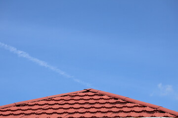 House roof with steel roofing sheet. Traditional metal shingle tiles. Building's covering with blue sky background