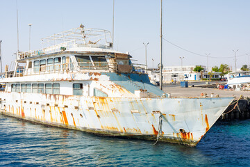 Rusty abandoned ship docked at harbor