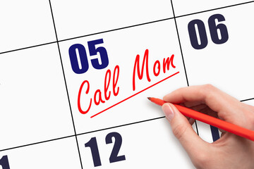 5th day of the month.  Hand writing Call Mom reminder and drawing a line on calendar with red pen...
