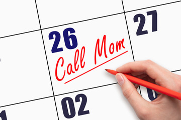 26th day of the month.  Hand writing Call Mom reminder and drawing a line on calendar with red pen...