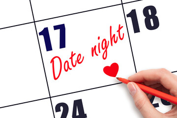 17th day of the month.  Hand writing Date night reminder and drawing a red heart on calendar with...