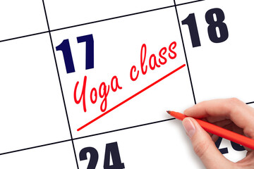 17th day of the month.  Hand writing Yoga class reminder and drawing a line on calendar with red...