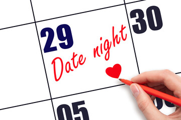 29th day of the month.  Hand writing Date night reminder and drawing a red heart on calendar with...