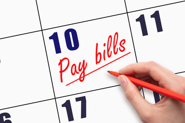 10th day of the month.  Hand writing Pay bills reminder and drawing a line on calendar with red pen...