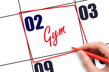 2nd day of the month. Hand writing Gym reminder and drawing red frame on calendar with red pen on...