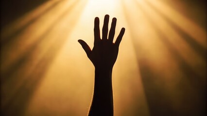 Silhouette of arm and hand reaching up towards a bright light shining from above in a dark background