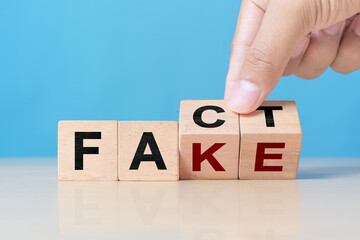 Business man hand holding wooden cube with flip over block FAKE to FACT. rumor News, false, myth,...