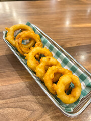 Crunchy fried battered onion rings served on a metal grid with a green patterned cloth.