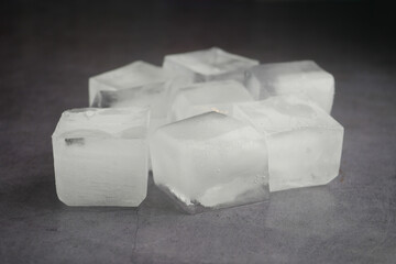 Clear ice cubes resting on dark surface for beverage cooling