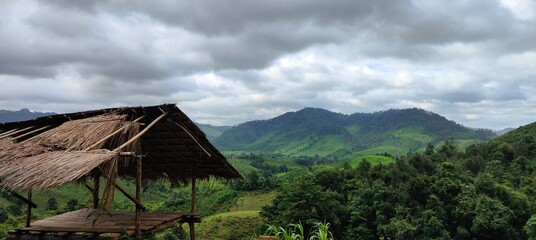 Tranquil View of a Traditional Hut and Green Mountains in laos. Rural Landscape with Thatched Hut...