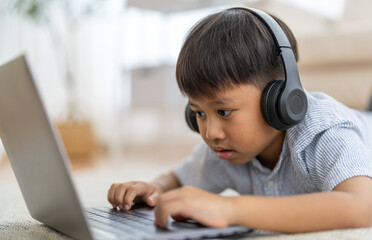 Asian boy using laptop with headphones course online learning, distance education for kids,...